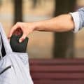 Pickpocket thief stealing wallet from woman handbag