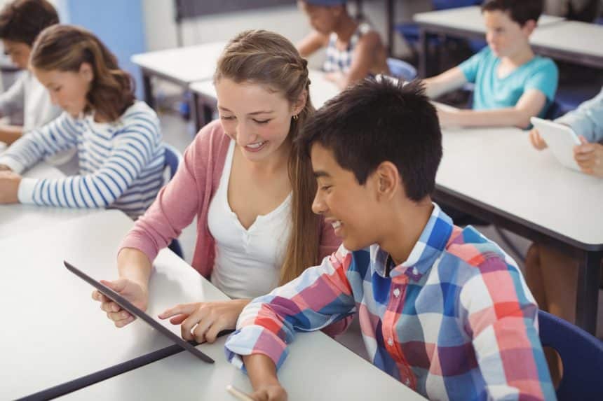 Students using digital tablet and laptop in classroom