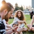 Group of young friends sitting on ground at summer festival