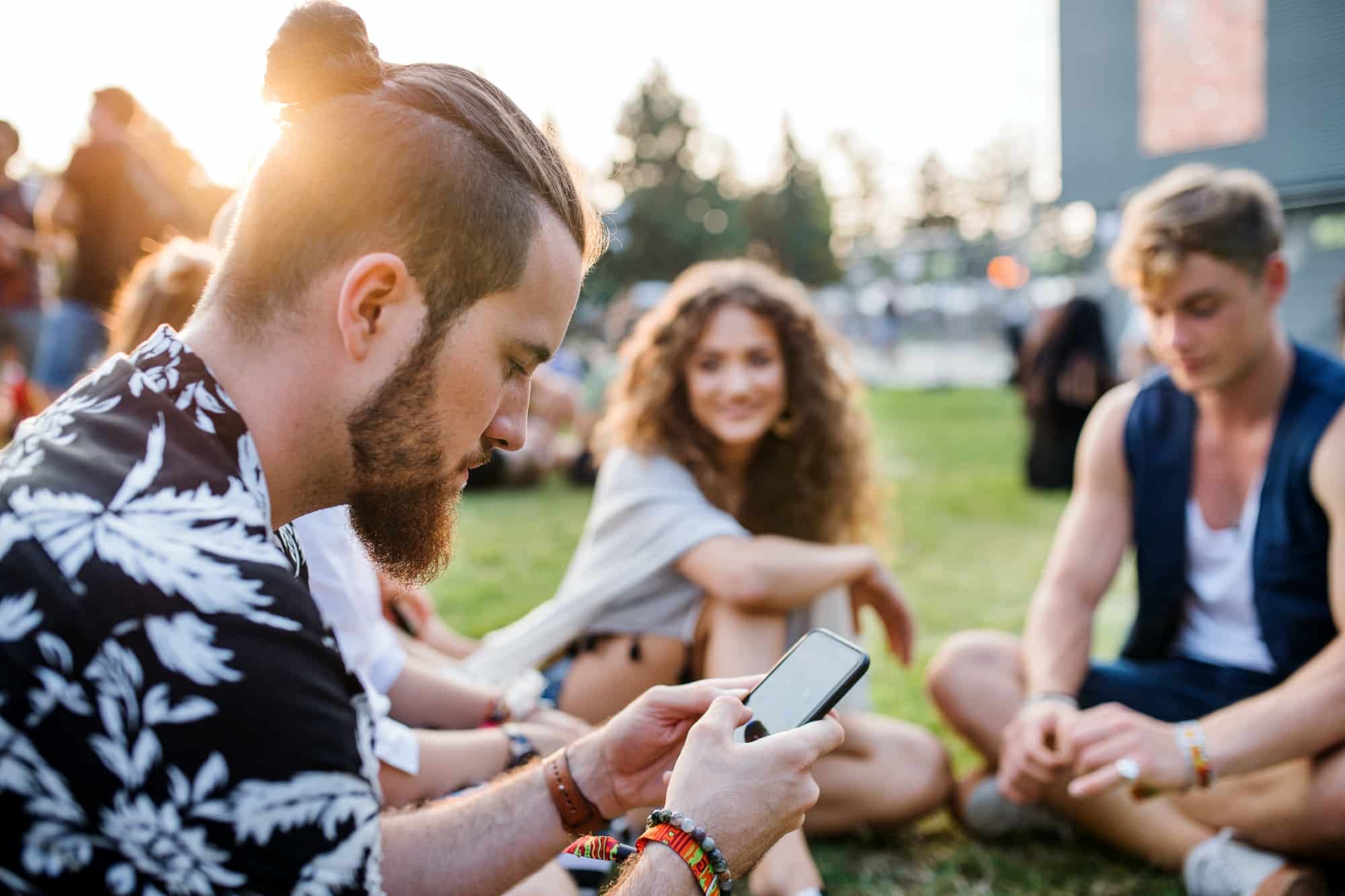 Group of young friends sitting on ground at summer festival