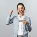 Technology, online and mobile lifestyle concept. Excited, happy triumphing asian woman winning prize