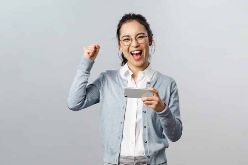 Technology, online and mobile lifestyle concept. Excited, happy triumphing asian woman winning prize