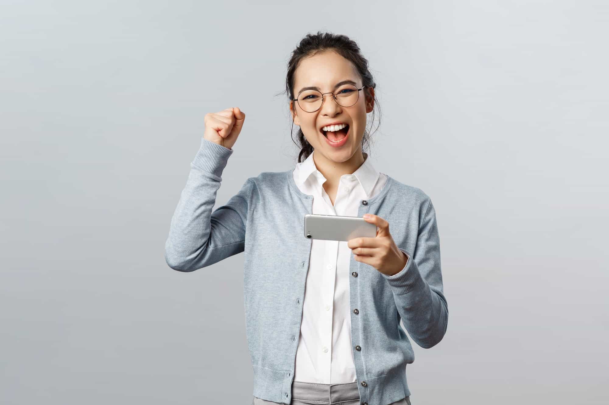 Technology, online and mobile lifestyle concept. Excited, happy triumphing asian woman winning prize