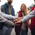 Close up of group of happy community service volunteers stacking hands together outdoors in street