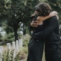 Husband trying to comfort his wife at a graveyard
