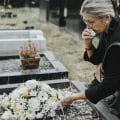 Old woman laying flowers on a grave