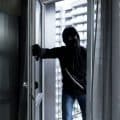 A male thief in a black mask, enters the apartment for robbery, the robber broke the door lock