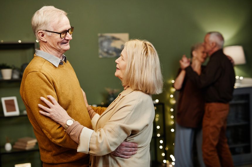 Old man and woman dancing indoors