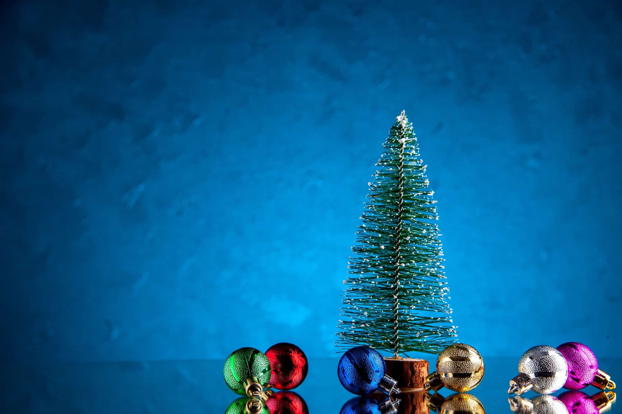 front view small xmas balls mini xmas tree on dark blue background with free space