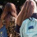Two high school girls walking into school with backpacks