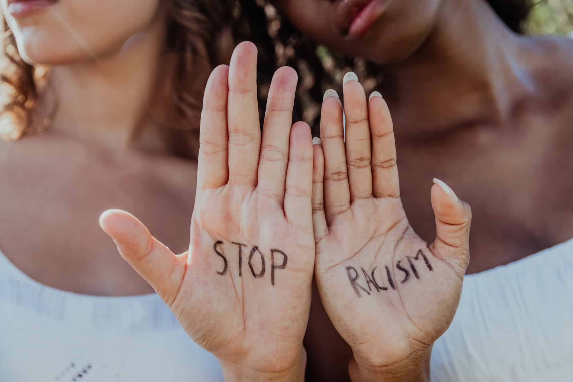 Close up of the hands of two women with written "Stop Racism".