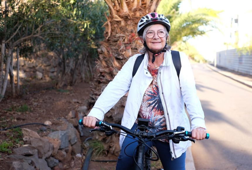 Sporty senior woman with bicycle helmet in healthy outdoor activity with electric bicycle