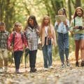 Walking together. Kids in green forest at summer daytime