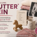 Symbolisches Artikelbild zur Ausstellung „Muttersein“ in der Stadtbibliothek Neheim mit Alltagsgegenständen, Textilien, Kinderzeichnung und Erinnerungsstücken.