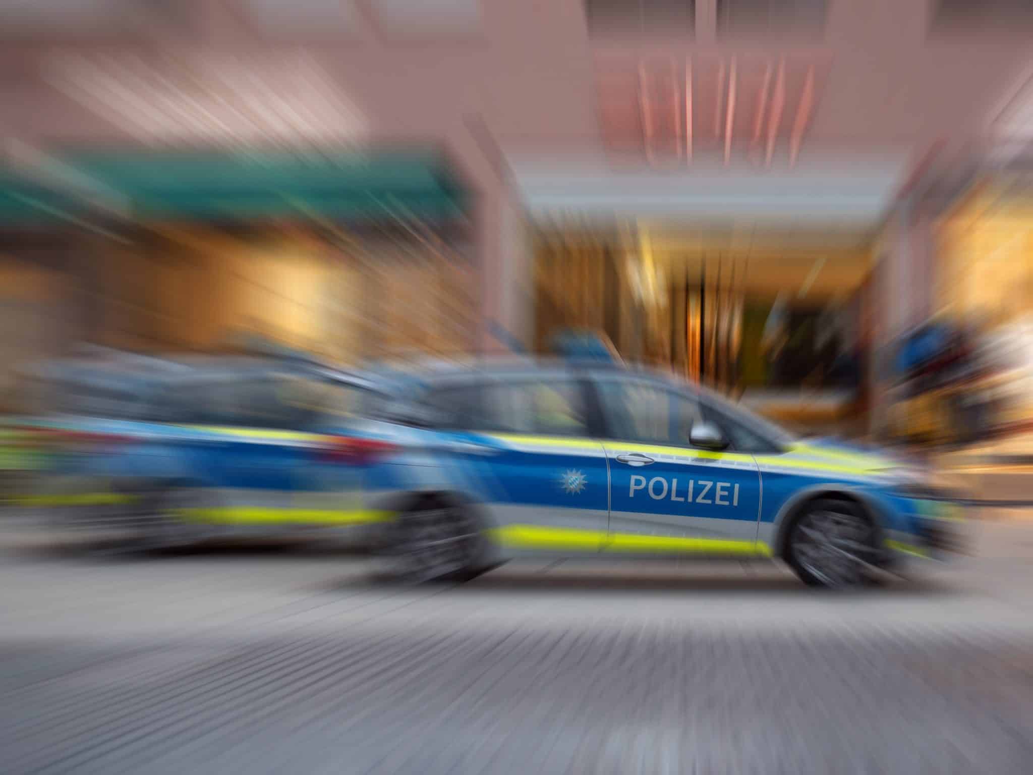 Deutscher Polizei-Streifenwagen mit POLIZEI-Schriftzug in Fahrt (Symbolbild)