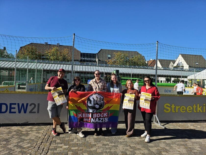 Sechs Beteiligte der Aktion ‚Kick Racism Out‘ stehen vor dem Streetkick-Court auf der Neheimer Marktplatte und halten ein Banner mit der Aufschrift ‚Kein Bock auf Nazis‘.