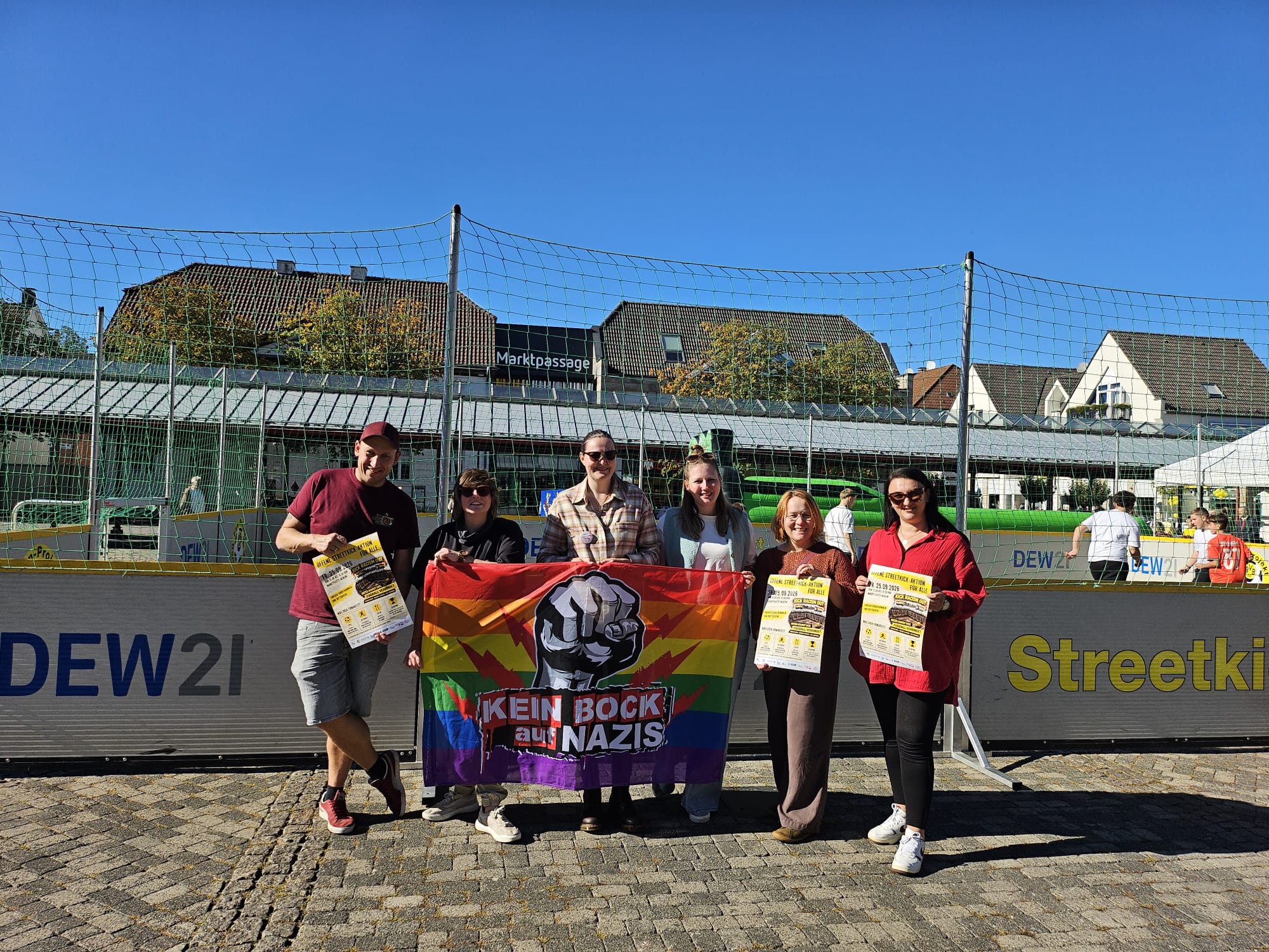 Sechs Beteiligte der Aktion ‚Kick Racism Out‘ stehen vor dem Streetkick-Court auf der Neheimer Marktplatte und halten ein Banner mit der Aufschrift ‚Kein Bock auf Nazis‘.